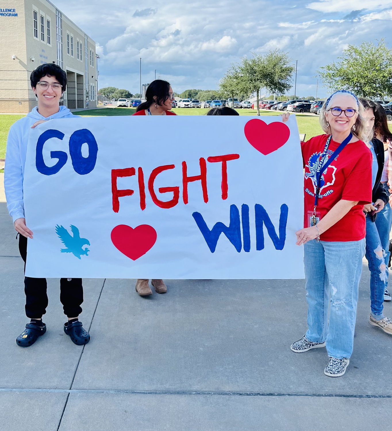 Royal High student Leo Robles, left, and teacher Lynette Beyer, right, hold up a banner supporting the Falcons. The Falcons enjoyed their first winning season and playoff berth since 2010.